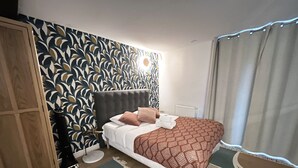 A bedroom with a bed, a wardrobe, a patterned wall, and a window with curtains. - Urban Flat 161 - Sublime 4BDR Luxury Flat in Paris (París)