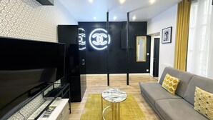 A modern living room with a flat-screen TV, a sofa, and a patterned wall. - Urban Flat 157 - Flat by Coco in Montorgueil (París)