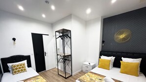 A hotel room with two beds, a wardrobe, a bedside table, and a wall-mounted fan. - Urban Flat 157 - Flat by Coco in Montorgueil (París)