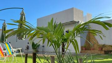 Un jardín con un edificio blanco, cerca de madera y una silla.