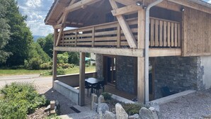 A wooden cabin with a stone facade, a balcony, and a table and chairs outside. - Le P'tit Curieux - Rupt-sur-moselle (Rupt-sur-Moselle)