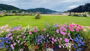 A park with a variety of colorful flowers and a lake in the background. - Le P'tit Curieux - Rupt-sur-moselle (Rupt-sur-Moselle)