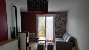 A modern living room with a sofa, a dining table, and a fireplace. - Maison 7 Personnes - Quartier Calme - Belle vue sur Charlannes (Murat-le-Quaire)