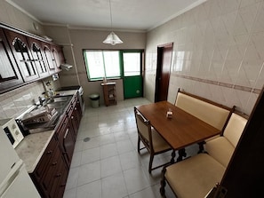 Uma cozinha com mesa e cadeiras, uma janela e uma porta verde.