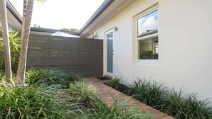 A modern house with a brick pathway leading to a door, surrounded by lush greenery. - Charming Studio Prime Location Steps from Beach (Fort Lauderdale)