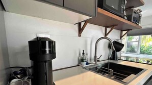 A kitchen with a coffee maker, a sink, and a window. - Charming Studio Prime Location Steps from Beach (Fort Lauderdale)