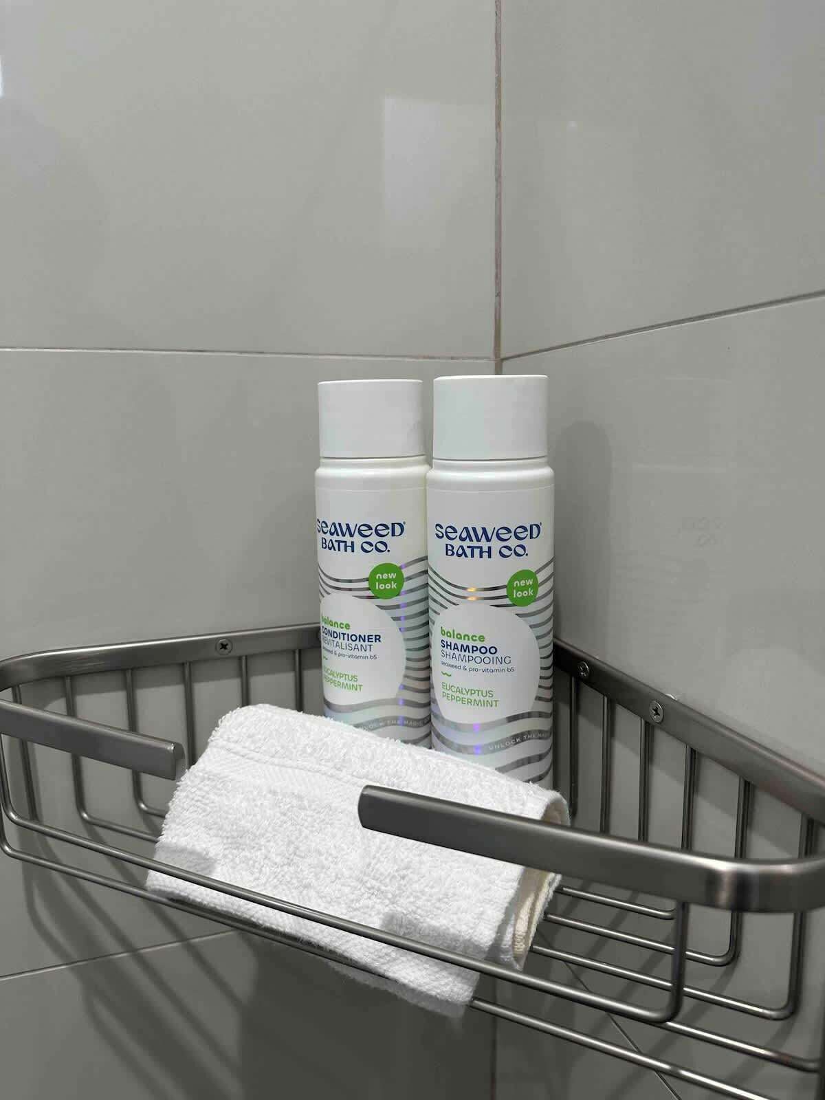 A metal basket with a white towel and two bottles of Seaweed Bath Co. products.