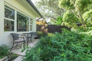 Una casa con un patio, dos sillas y una mesa.