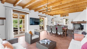 A spacious living area with a high ceiling, wooden beams, a dining set, and a fireplace. - Beautiful Villa Habibi with pool (Sovinjak)