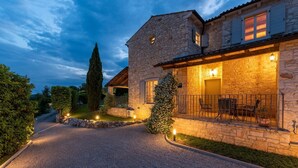A stone house with a gravel driveway, a patio with outdoor furniture, and a well-lit entrance. - Beautiful Villa Habibi with pool (Sovinjak)