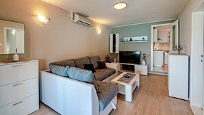 A compact living space with a sofa, TV, and kitchenette. - Holiday House with Sea View (Vela Luka)