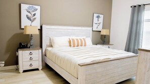 A bedroom with a wooden bed, two bedside tables with lamps, and artwork on the walls.