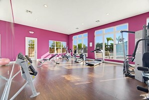 A gym with cardio machines, weight training equipment, and large windows.