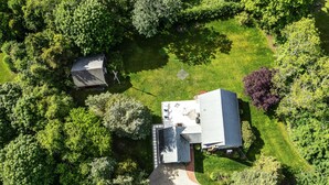 An aerial view of a residential area with a large house, a smaller building, and a driveway.