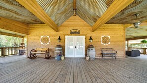Eine Veranda mit Holzboden und -dach, einer weißen Tür, Holzbanken und Laternen.