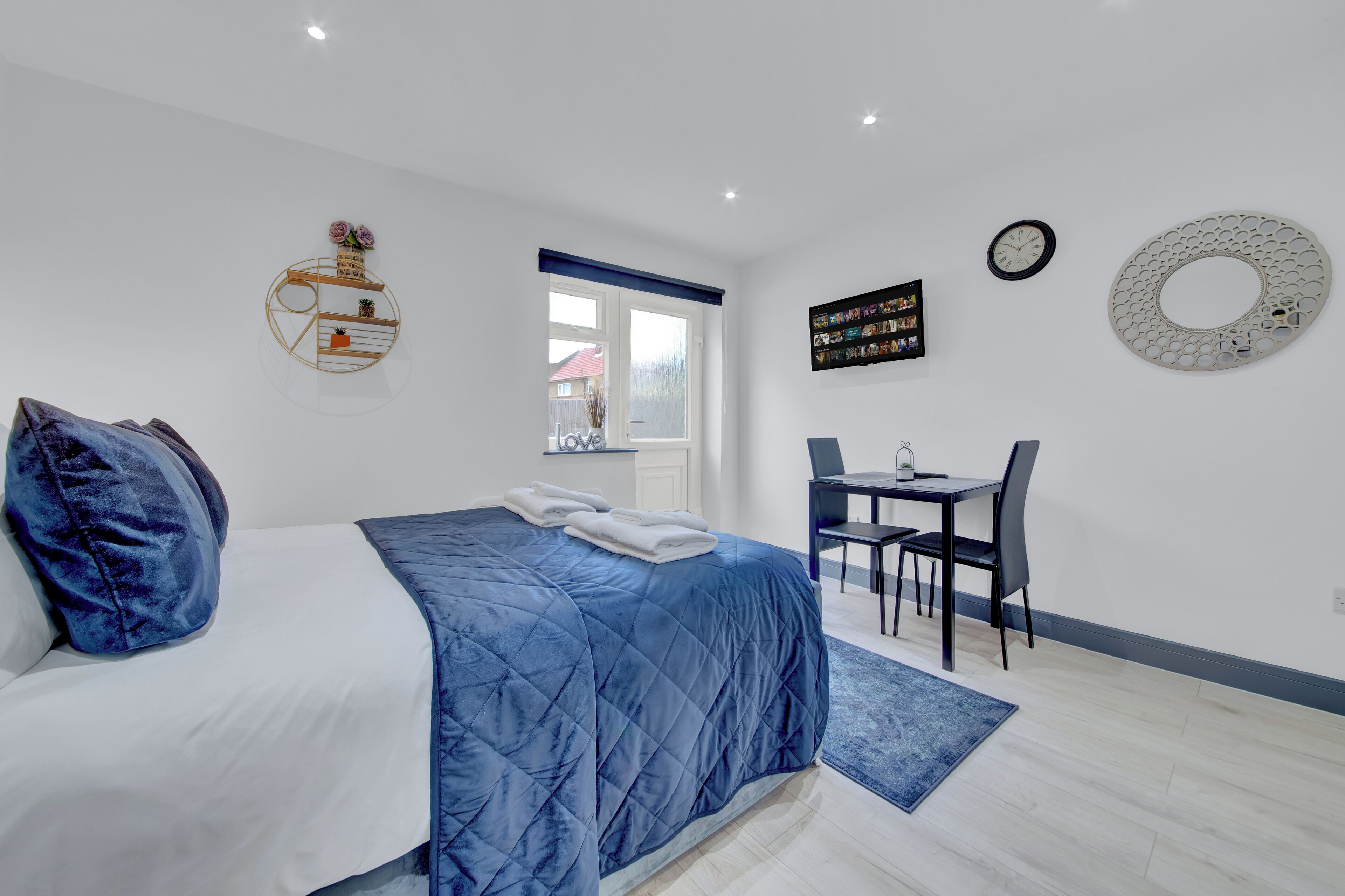 A bedroom with a bed, a desk, and a chair.
