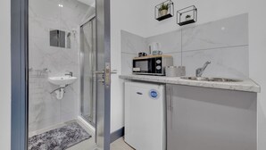 A compact bathroom with a glass shower enclosure, a sink, and a compact refrigerator. - Lovely 1-bed Studio in Feltham (Feltham)