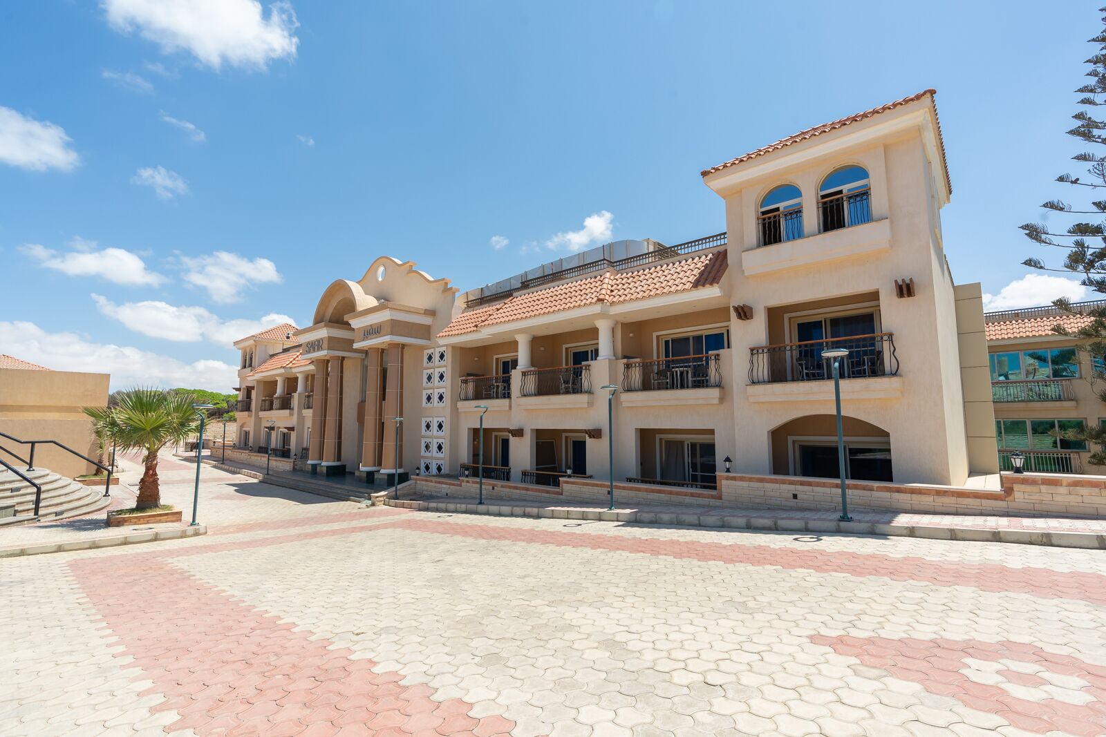 Un hotel de varios pisos con un patio central, balcones y un techo de tejas.