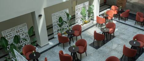 A spacious indoor area with multiple tables and chairs, white decorative partitions, and potted plants.