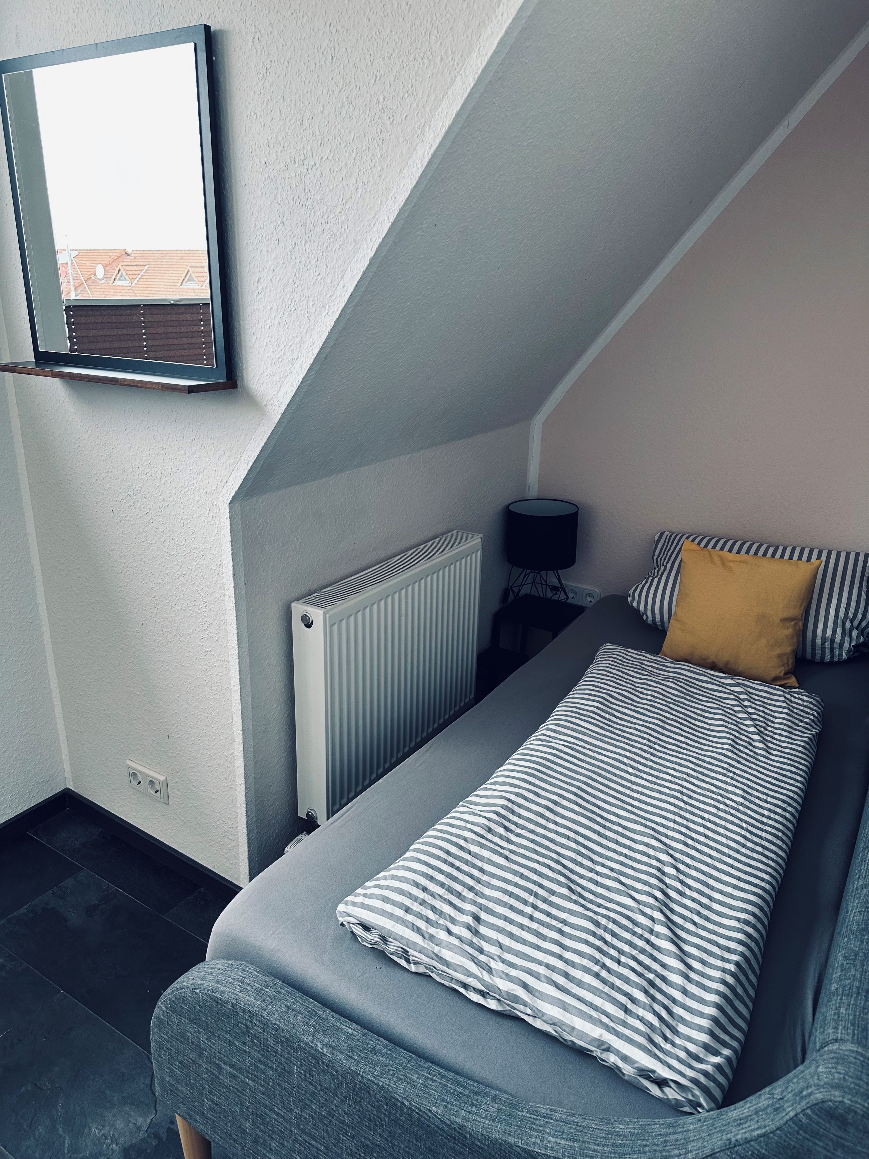 Ein Schlafzimmer mit einem Bett, einem Heizkörper, einer Lampe und einem Fenster.