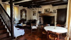 A traditional living room with a fireplace, wooden furniture, and a staircase. - Maison Périgourdine en Pierre Nature Avec Piscine (Saint-Jory-las-Bloux)