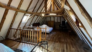 A cozy attic bedroom with a sloped ceiling, wooden beams, a bed, a desk, and a chair. - Maison Périgourdine en Pierre Nature Avec Piscine (Saint-Jory-las-Bloux)
