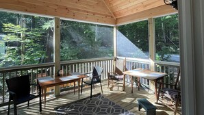 A covered porch with wooden flooring, a patterned rug, and a wooden table with chairs.