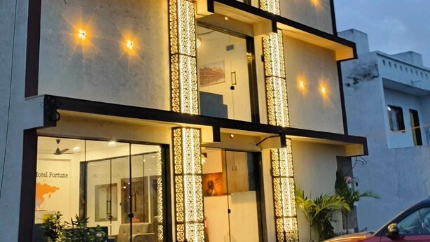 A multi-story hotel with a modern design, featuring balconies, large windows, and decorative light fixtures. - Hotel Fortune (Surat)