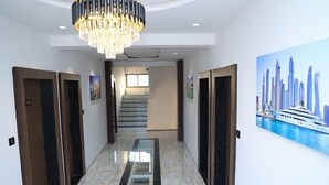 A hotel hallway with a marble floor, wooden doors, a chandelier, and a cityscape painting on the wall. - Hotel Fortune (Surat)