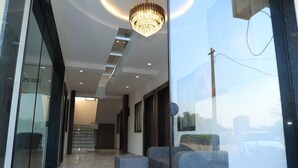 A modern interior with a marble floor, a chandelier, and a view through a glass wall. - Hotel Fortune (Surat)