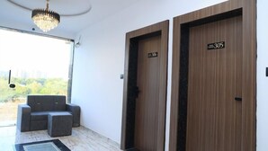 A modern hotel lobby with a glass partition, a chandelier, and two doors labeled 306. - Hotel Fortune (Surat)