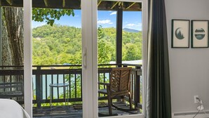 A room with a sliding glass door leading to a balcony with a view of a forested landscape. - Cozy Sugar Ski - 4 Ensuites, Extremely close to Slopes, Tubing, and Ice Skating! (Sugar Mountain)