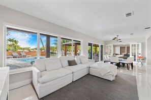 Living room area with access to pool dining table cloud sofa and flat screen tv