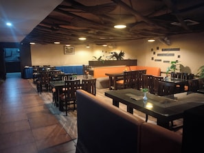 Un restaurant avec des tables et des chaises en bois, une moquette bleue et un plafond en bois.