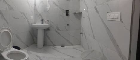 Un baño con inodoro, lavamanos y zona de ducha.
