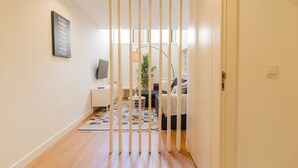 A hallway leading to a living area with a TV, a plant, and a sofa. - Delightful Duplex by LovelyStay (Vila Nova de Gaia)