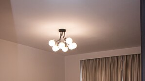 Une chambre spacieuse avec un grand lit, une tête de lit capitonnée et un lustre moderne.