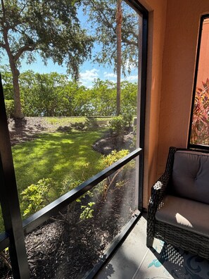 Una habitación con un amplio ventanal que da a un jardín con árboles y césped.