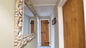 A hallway with a large ornate mirror, wooden doors, and a carpeted floor. - 1 Dolphin Cottages (Lyme Regis)