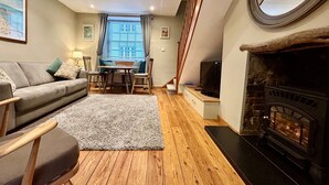 A cozy living room with a sofa, a coffee table, and a fireplace. - 1 Dolphin Cottages (Lyme Regis)