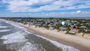 A coastal residential area with houses along the beach, a clear sky, and a calm sea.