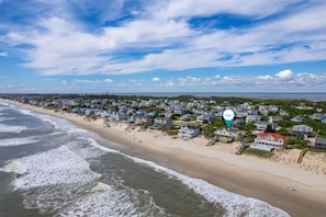 A coastal residential area with houses along the beach, a clear sky, and a calm sea.