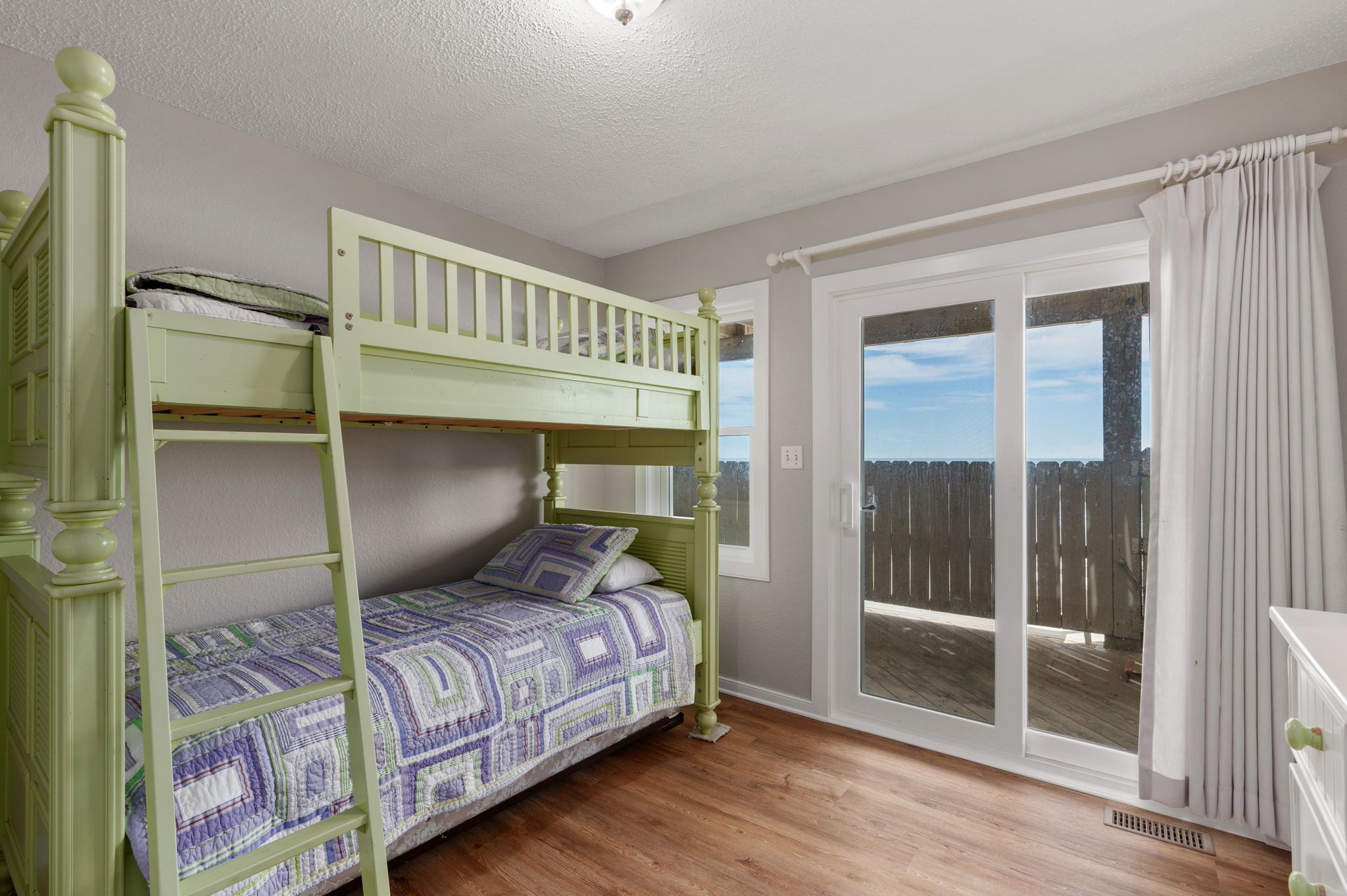 Een kamer met een stapelbed, een raam met uitzicht en een deur naar een buitengebied.