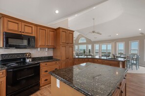 Una cocina amplia con encimeras de granito, armarios de madera y una isla grande.