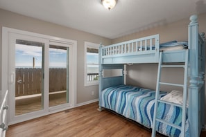 Ein Zimmer mit einem Etagenbett, einer Schiebetür zu einer Terrasse und einer Deckenleuchte.