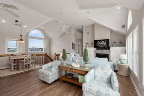 A spacious living room with a dining area, a kitchen, and a large window offering a view of the mountains.
