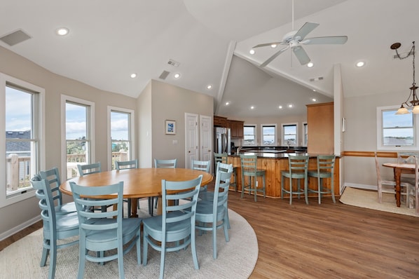 A spacious kitchen with a central island, wooden flooring, and a dining area with a round table and chairs.