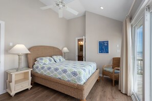 A bedroom with a bed, bedside tables, a ceiling fan, a window with curtains, and a wall map.