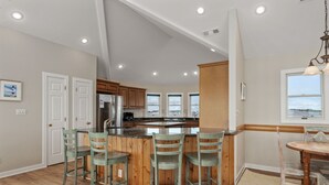 A kitchen with a central island, wooden cabinets, and a view through the windows.