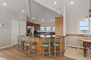 Una cocina moderna con una isla central, taburetes de madera y una mesa de comedor con sillas.
